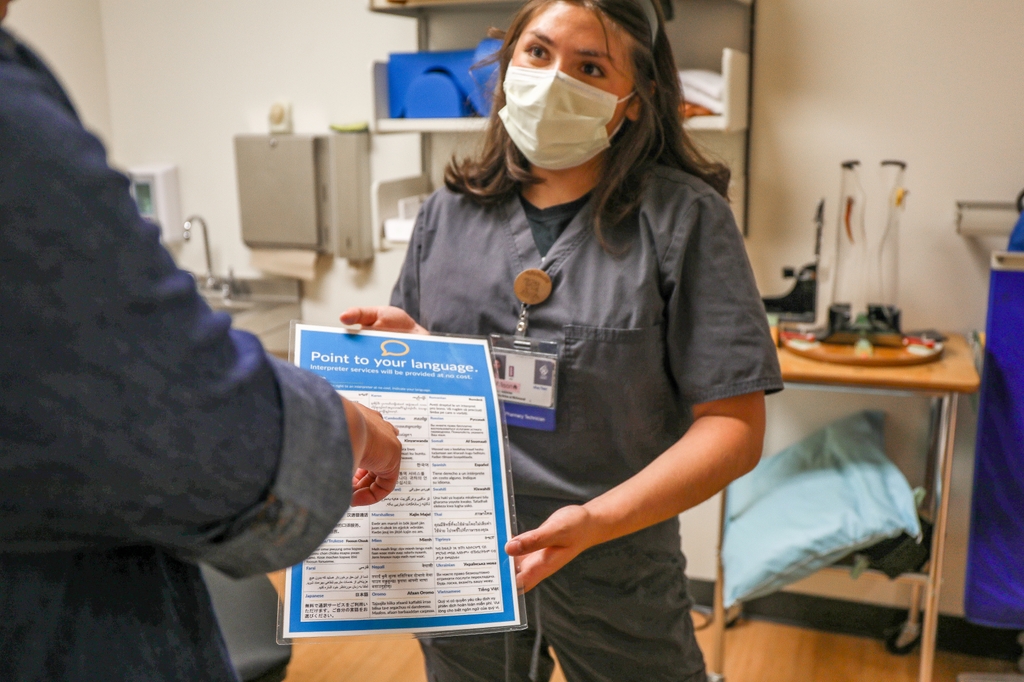 Una profesional de OHSU con un paciente que no habla inglés lo ayuda a identificar su idioma para los servicios de interpretación. Los equipos de atención médica de OHSU diagnosticaron encefalitis autoinmune a Frank Sánchez-Cacatzum, de 4 años, después de que sus padres de habla hispana se sintieran desestimados por otros profesionales de la salud. (OHSU/Christine Torres Hicks)