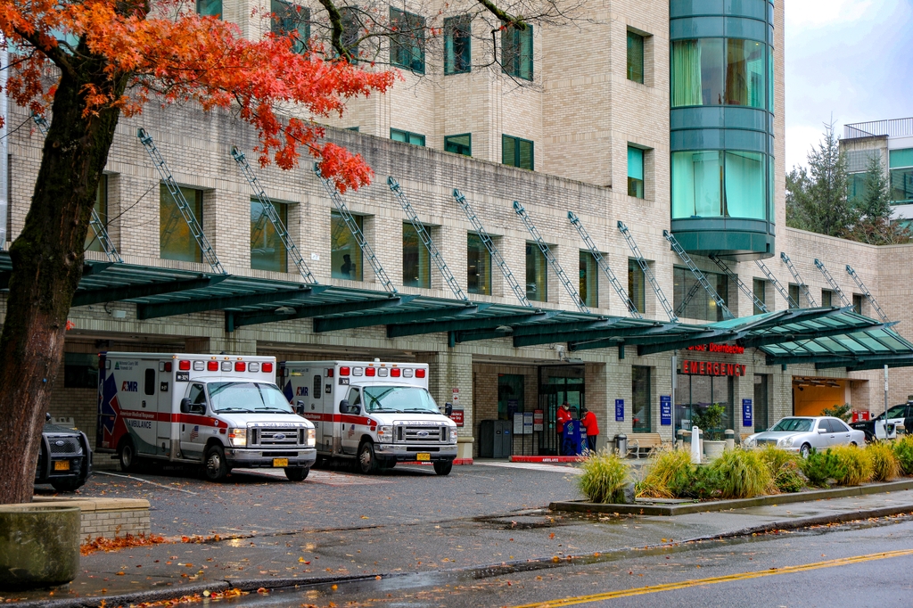 Image is of the exterior of the OHSU Emergency Department building with ambulance vehicles nearby parked in view. Led by the OHSU Gun Violence Prevention Research Center, the new Gun Violence Review Commission will apply a public health approach to analyze causes of gun violence in Multnomah County, and drive toward solutions. (OHSU/Christine Torres Hicks)