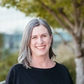 Laurie King, Ph.D., PT, MCR, tiene cabello gris/rubio hasta los hombros, una blusa oscura y sonríe en un balcón de OHSU.