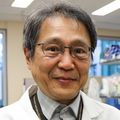 Hiroyuki Nakai, M.D., Ph.D., has short, straight, black hair, eye glasses and a white coat. He is smiling in the lab.