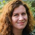 Maureen Baldwin, M.D., M.P.H., tiene el cabello castaño rizado y rizado hasta los hombros y un abrigo azul, y sonríe en un jardín de OHSU.
