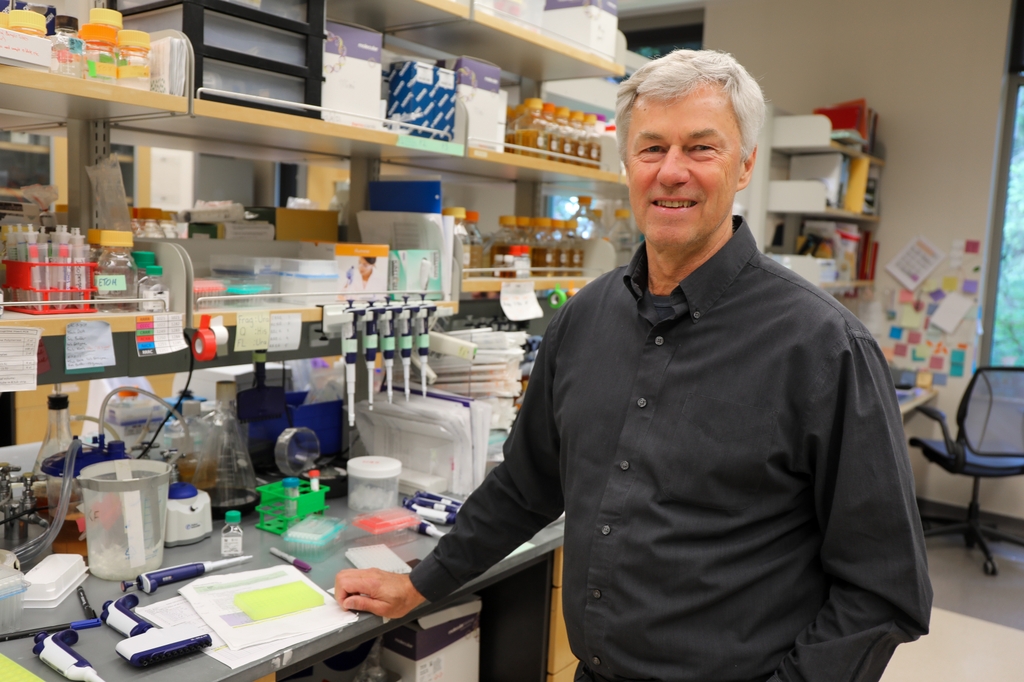 Klaus Frueh, Ph.D., tiene el pelo corto y gris y sonríe en su laboratorio del Instituto de Terapia Génica y Vacunas. (OHSU/Christine Torres Hicks)