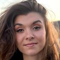 Erin Santos has shoulder-length brown hair, standing on a balcony during sunrise. 