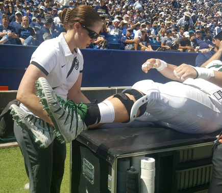 Jacqueline Brady helps an athlete on the Portland State University sports field.