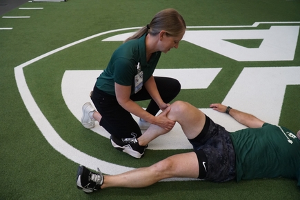 Melissa Novak helping someone on a sports field at Portland State University.