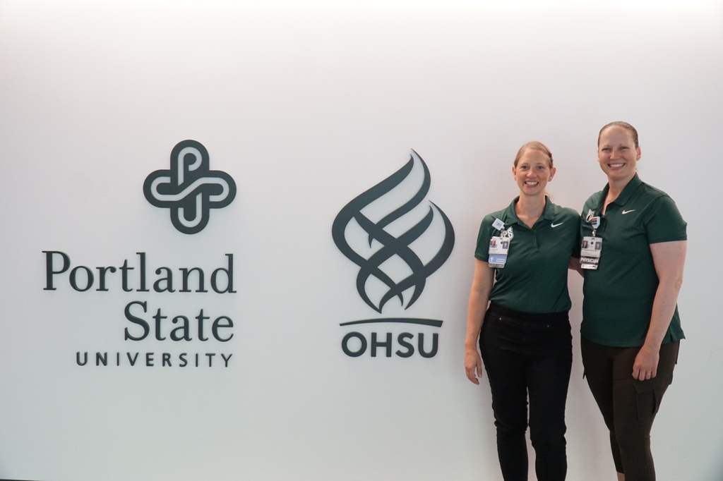 Melissa Novak, D.O., and Jacqueline Brady, M.D. stand near an OHSU/Portland State wall sign.