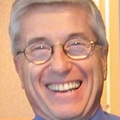 Archie Bleyer, M.D., tiene el pelo corto, blanco y gris, usa anteojos y sonríe.