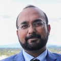 Sushant Puri, M.D., has on a blue suit, and has short dark hair, facial hair, and eyeglasses, standing on a balcony of CHH1 at OHSU.
