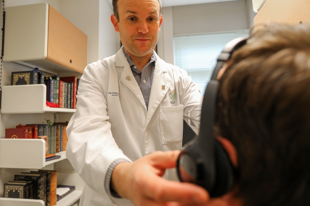 El Dr. Lee Neilson, M.D. demuestra el uso de auriculares, que usa para hacer pruebas de audición a los pacientes. Neilson es el autor de un estudio nuevo en el que se sugiere una asociación entre la pérdida de audición y el desarrollo del mal de Parkinson. (OHSU/Christine Torres Hicks)