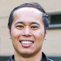 Leo Han, M.D., M.P.H., tiene el pelo corto y oscuro, lleva una chaqueta de OHSU y sonríe afuera del Instituto de Vacunas y Terapia Génica.