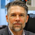 Owen McCarty, Ph.D., tiene el pelo gris peinado hacia un lado, un traje y sonríe mientras está sentado en su laboratorio en CHH1.