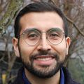 André L. Lira, Ph.D., tiene el pelo corto y oscuro peinado hacia un lado, un suéter negro y sonríe en el patio del CHH1.
