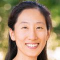 Vanderlene Kung, M.D., Ph.D., has long, black hair pulled back on top, and is wearing a magenta top, smiling in a nature area.