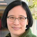 Miranda Lim, M.D., Ph.D., has shoulder-length black hair, eye glasses and a green sweater, smiling in a hallway at OHSU.