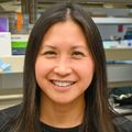 Jamie Lo, M.D., M.C.R. (OHSU) tiene el pelo largo y oscuro y lleva un suéter negro, parada en su laboratorio en OHSU.