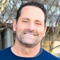 Brian Scottoline, M.D., Ph.D., tiene cabello castaño corto, un suéter azul y sonríe en la cubierta del CHH1.