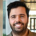 José Montoya Mira, Ph.D., tiene el pelo negro corto con raya a un lado y una camisa verde oliva, y sonríe en los pasillos del Knight Cancer Institute.