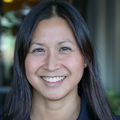 Jamie Lo, M.D., M.C.R. has long dark hair, a black shirt, smiling.