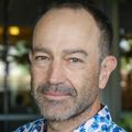 Matthias Schabel, Ph.D. has very short brown hair and facial hair, a shirt with pineapples on it and smiling in a garden area at OHSU.