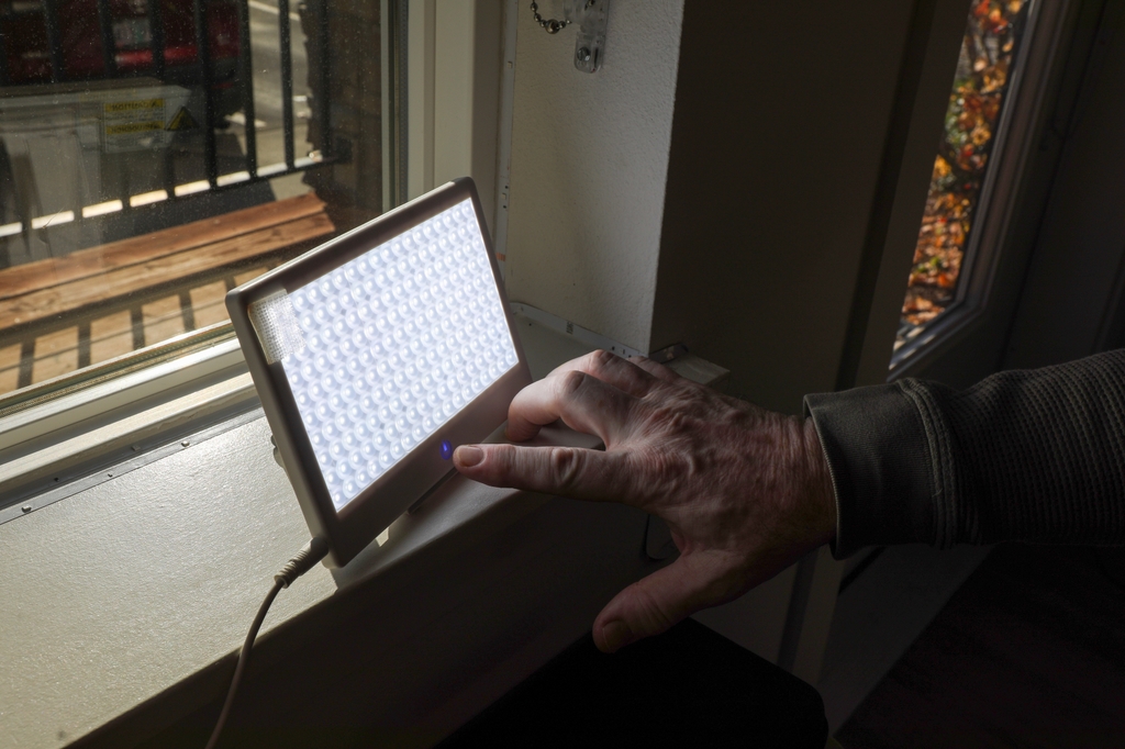 Cary "Jack" Glenn, veterano de la Marina, demuestra el uso de la terapia de luz&nbsp;brillante en su casa en el suburbio de Happy Valley, en Portland. (OHSU/Christine Torres Hicks)