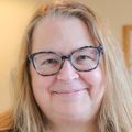 Andrea DeBarber, Ph.D., has long blonde hair, eye glasses and a dark shirt on.