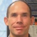 Igor Landais Ph.D. has short dark hair and a gray top, he is smiling in the lab.