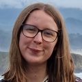 Franka Westermann, Ph.D. has shoulder-length dark blonde hair, eye glasses, a flowered shirt, smiling near the ocean.