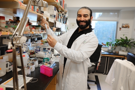 Karimi smiles while holding equipment in his lab.