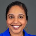 Neha has black hair pulled back and is wearing a bright royal blue shirt.