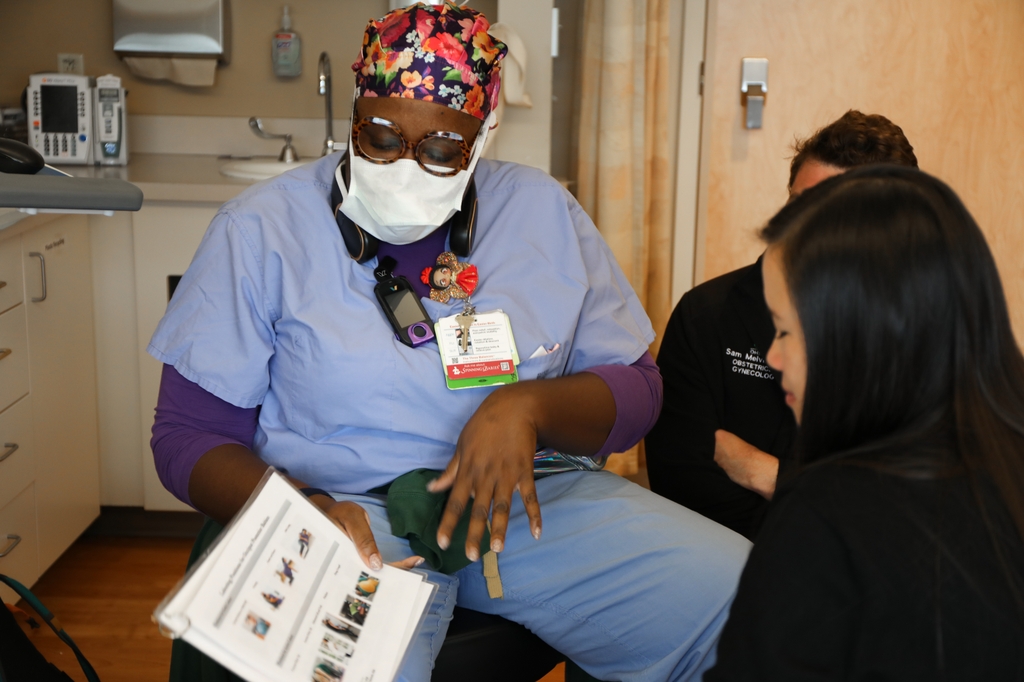 OHSU labor nurse holds a guide for labor options as two doctors look on in a patient room at OHSU Labor and Delivery.