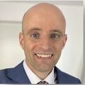 Ryan has no hair and is wearing a suit.