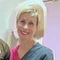 Carlee has short blonde hair and a hot pink shirt, smiling next to an unidentified man.