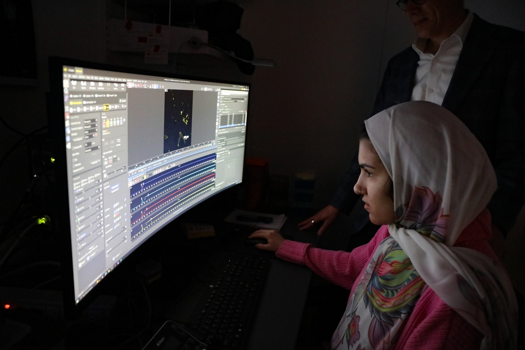 Una mujer en el laboratorio de Alexander Davies mira datos de cáncer en una pantalla de computadora.