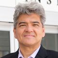 Andreas tiene el pelo cano y viste traje, de pie enfrente del Casey Eye Institute de OHSU.