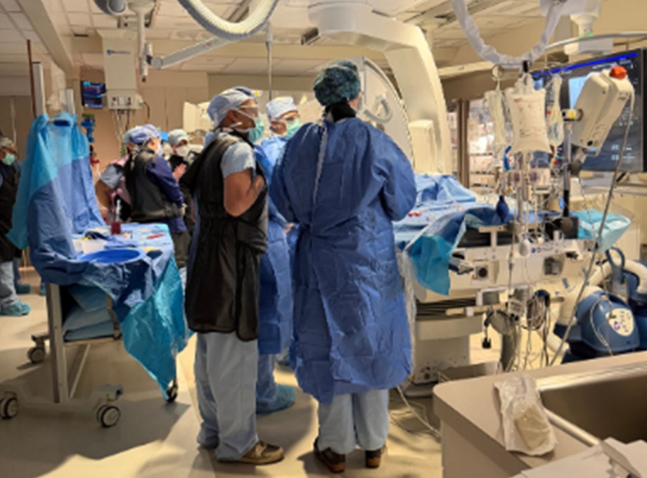La imagen muestra a un equipo de cirujanos y otros profesionales médicos(as) preparados con la higiene necesaria en un quirófano.