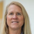 Rosalie has straight, shoulder-length blonde hair and is wearing a sky blue dress shirt, smiling in the Robertson Life Sciences Building.