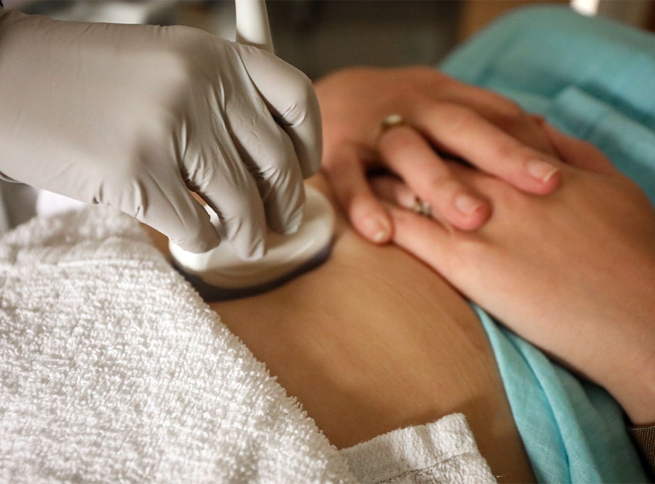 Clinician at OHSU in Portland performs an abdominal ultrasound exam, illustrating medical care related to miscarriage and pregnancy complications.