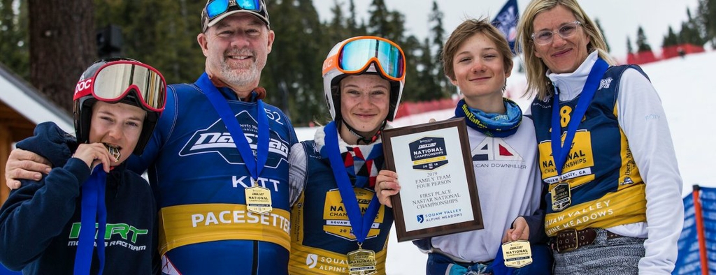 La foto es de los cinco miembros de la familia Kitt vistiendo trajes de esquí azules, sosteniendo premios y medallas del evento y sonriendo.