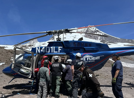 Life Flight Mount Hood Team surrounding the helicopter atop the mountain.