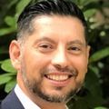 Jorge has short black hair and is wearing a suit.