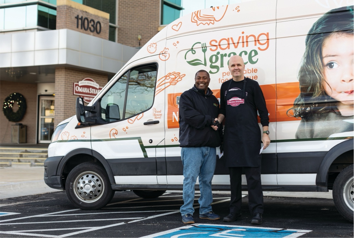 Two men standing in front of Saving Grace food delivery truck