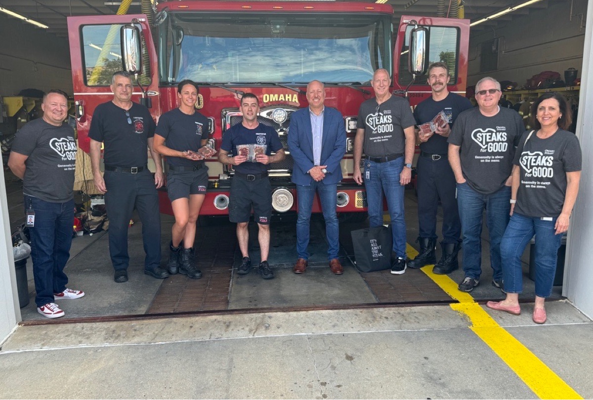 A group of firefighters standing in front of a fire truck at a station