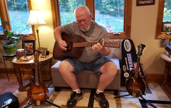 Tom Sharpe plays the guitar at his house in Winston-Salem