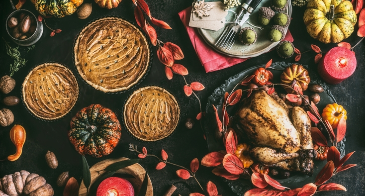 Thanksgiving day dinner table with pumpkin pie, roasted turkey and festive autumn decoration and candles
