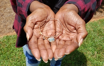 Joyce McNeill holds a bracelet her children gave her with the words Healing takes love inscribed on it