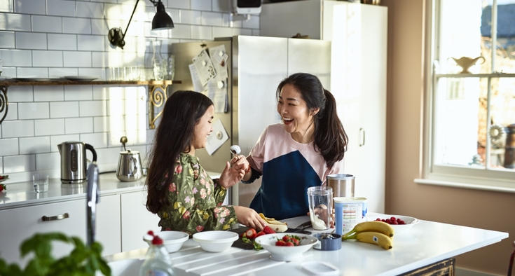Mother teasing daughter in kitchen whilst making smoothies