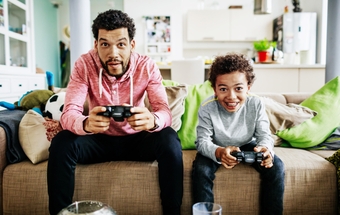 Father And Son Concentrating While Playing Video Games Together