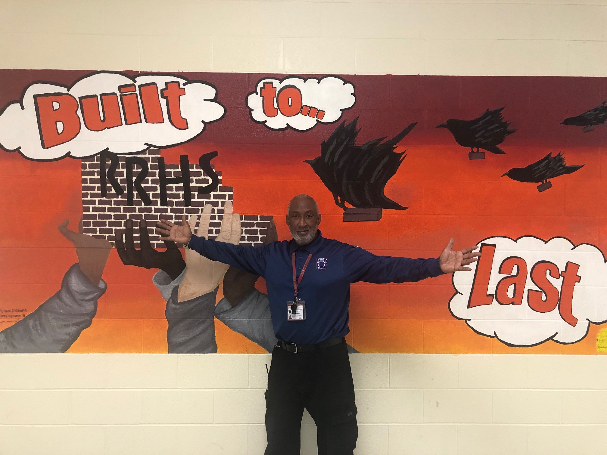 Reggie Hogans stands in front of one of the murals at Rocky River High School.