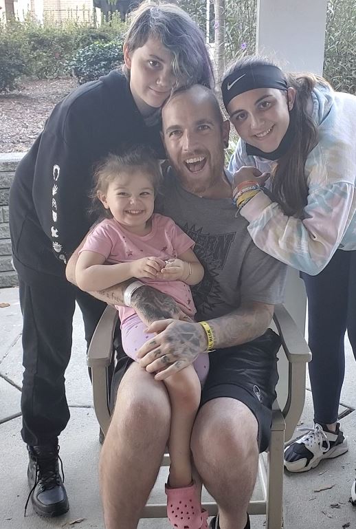 Jamie Calcasola smiles alongside his daughters, ages 2, 11 and 13. 