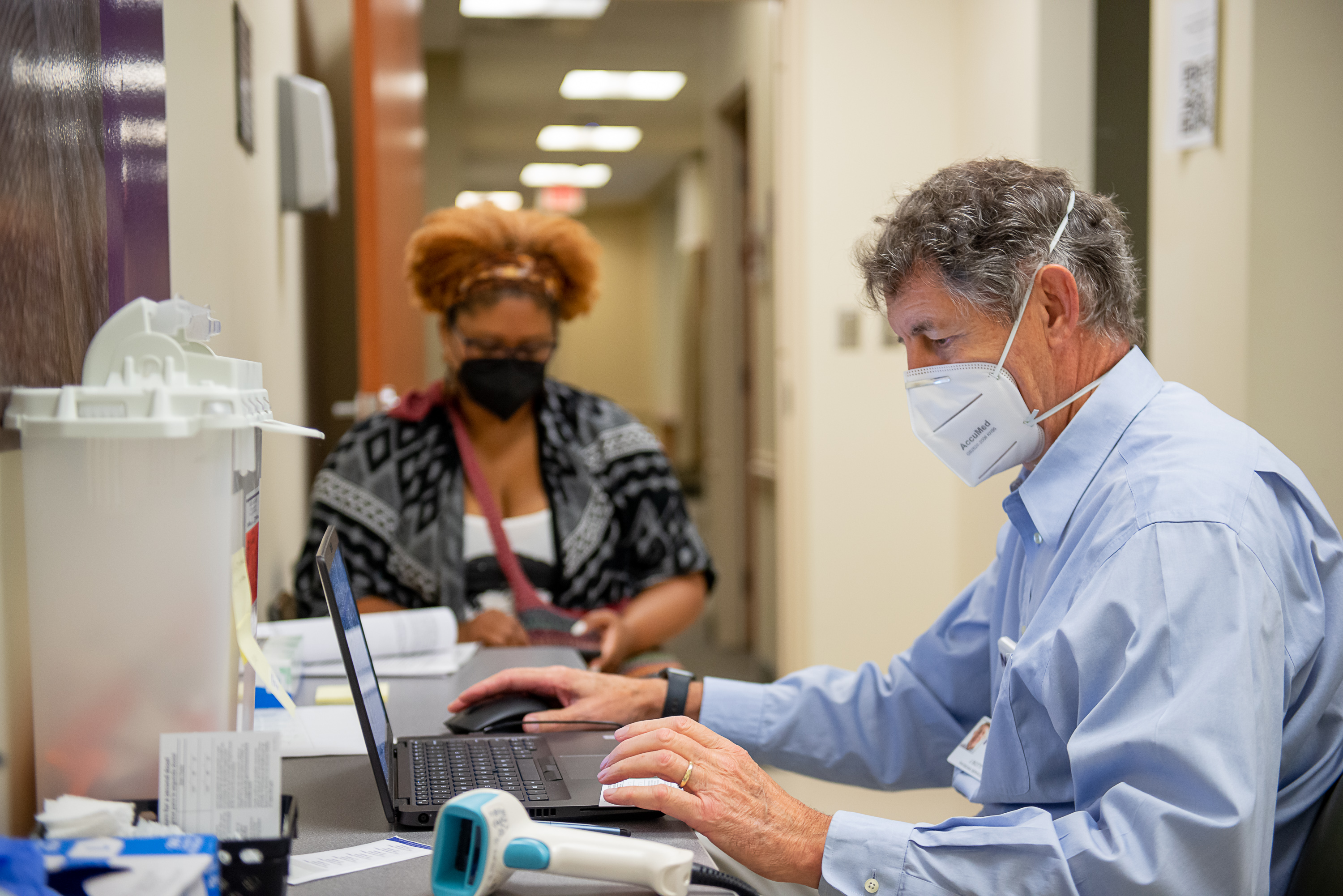 Dr. John Botti talks with a black woman before she gets the COVID-19 vaccination.